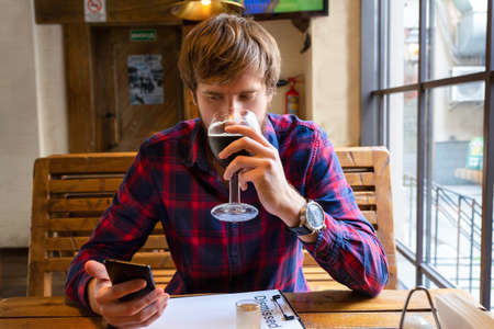 Young man drinking beer in a pub. An unemployed young man with problems sits in a bar alone and...