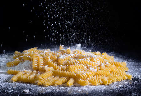 Yellow Italian pasta, spaghetti in flour against the black isolated background.の写真素材