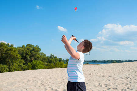 Boy playing badminton on the beach, on a sunny summer day. Sports lifestyle, recreation, sports, vacations.の写真素材
