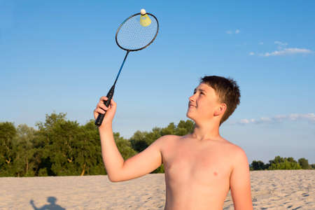 Boy playing badminton on the beach on a sunny day. Sports summer games on vacation, healthy lifestyle.の写真素材