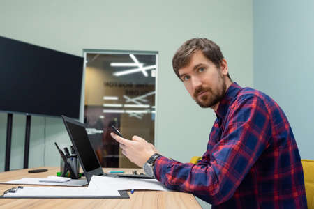 Young businessman working in the office sitting at his desk, looking to the side. Side view.の写真素材
