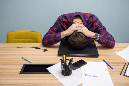 Tired young employee sleeping at the office table at work in the office. Business startup and entrepreneurship concept.の写真素材