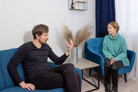 A man sitting on the couch, in consultation with a psychologist in the office, talks about his problems. Depression, crisis, psychological counselor concept.の写真素材