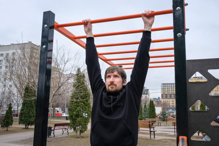 Young man making pulling exercises at the crossbar at the city playground. Fitness, Sport, Exercise, Healthy Lifestyle.の写真素材