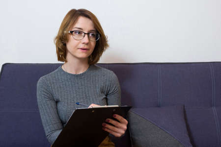 Young psychotherapist takes notes in a notebook. Healthcare concept of a professional psychologist doctor.の写真素材
