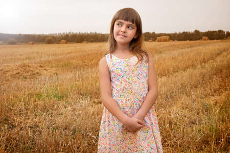 Portrait of a girl in a sundress in a field, on a sunny day. Children in nature. family weekend...