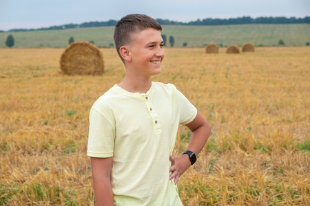 Happy teenager in a field of mown grass at the farm. Family weekend lifestyleの写真素材