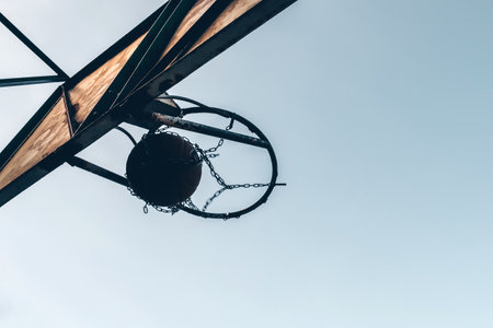 Basketball ball passing through the hoop outdoors against the backdrop of the sky. Sports concept.の写真素材