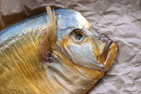 Cold smoked fish vomer on crumpled parchment on the table close-up. Top view.