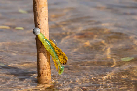 Spinning rod with silicone bait on the river close-up. Tackle for fishing. Fishing in nature.の写真素材