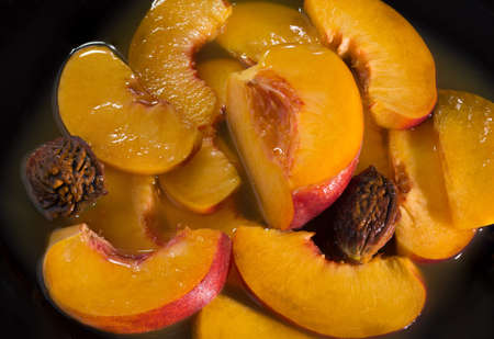 Juicy ripe peaches in own juice. Close up. On a black background