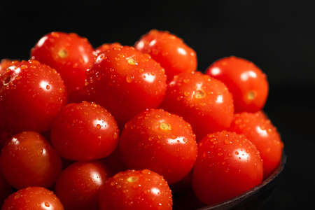 Red raw tomatoes with water drops on a black background. Healthy food conceptの写真素材