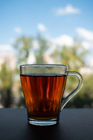 A glass cup of fragrant tea stands near the windowの写真素材