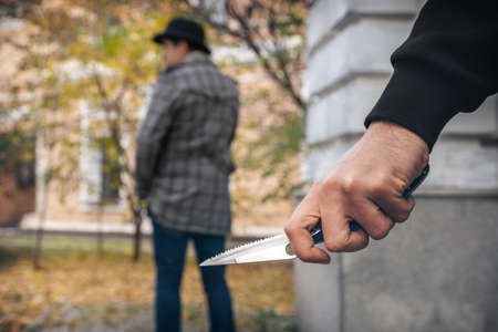 A man holding a knife in his hand ready to attack a man. Crime is on the riseの写真素材