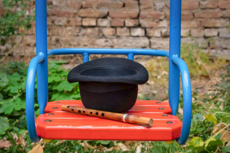 A black hat and a wooden sopilka lie on a swing in the playground.の写真素材