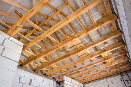 New construction of a wooden roof. Wood girder beams for new roof construction at construction siteの写真素材