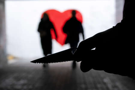Silhouette of a hand with a knife on the background of people in the underpass. Violence conceptの写真素材