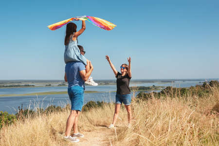 Happy family with a kite playing in nature on a sunny day.の写真素材