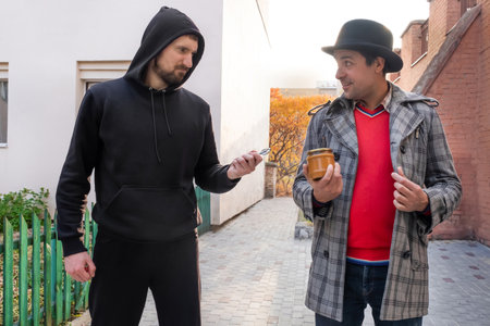 A robber with a key robbing a can of food from a man on a city street. Humor conceptの写真素材