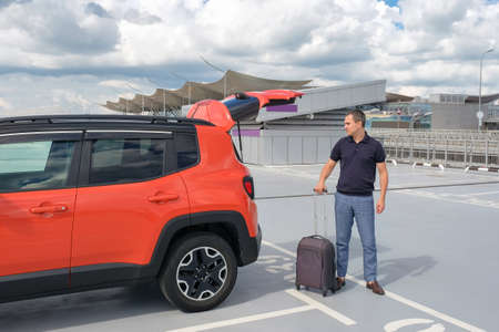 A man with a suitcase in his hands standing near the car.の写真素材