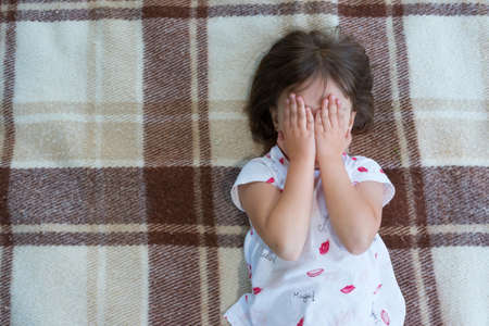 The child is covering the eyes with hands. The view from above.の写真素材