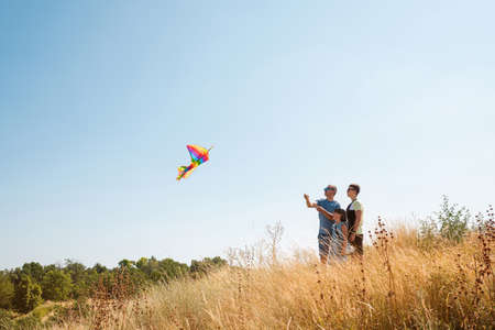 Happy family father with children fly a kite in the field outdoors. Side viewの写真素材