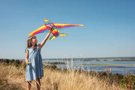 Little girl with a kite in her hands outdoors on a sunny dayの写真素材