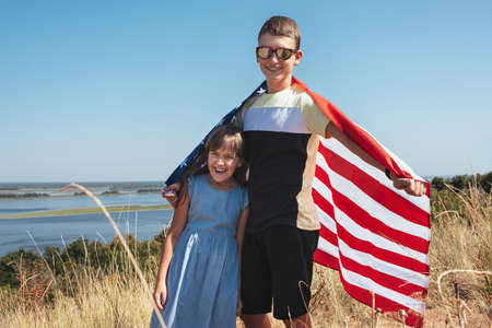 Happy kids playing with American flag outdoorsの写真素材