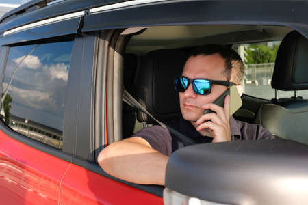 Portrait of a business man in a car talking on the phoneの写真素材