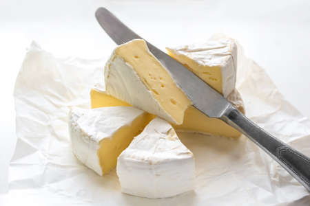 Brie cheese and kitchen knife in craft white paper. camembert cheese