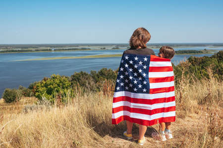 Back view of loving mother with daughter and with american flag enjoy nature.の写真素材