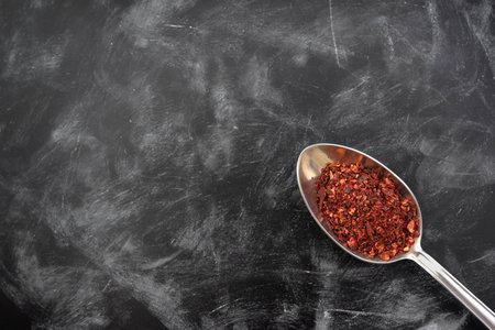 Spoon with spice on a dark kitchen table. Top view, Indian spices