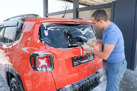 A man washing a car with soap, car wash. Car in foamの写真素材