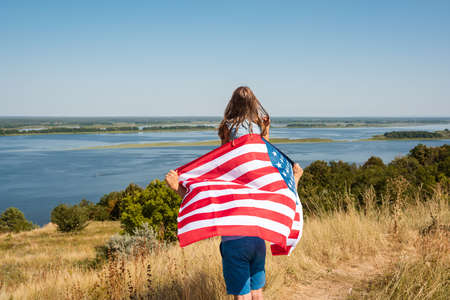 Father and daughter holding american flag enjoy nature, view from the back. freedom conceptの写真素材