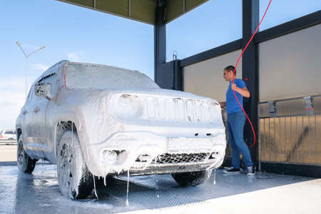 Car in the foam at the car wash. A man washes a car with soapの写真素材