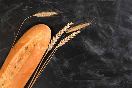 Fresh french bread and ears of wheat on a dark table. Fresh fragrant bread on the tableの写真素材