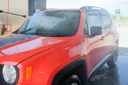 Washing a red car with high pressure water. Car at the car washの写真素材
