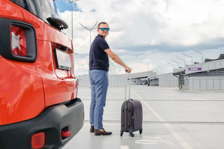 Young man with luggage in airport car park. Business trip, Travel conceptの写真素材