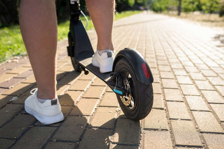 Man on a modern electric scooter in the park, close-up. Eco friendly transport.の写真素材