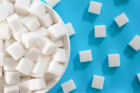 Background of sugar cubes in a plate on a blue background. Cubic sugar backgroundの写真素材