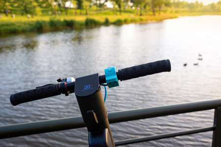 Electric scooter close-up in the park against the background of water on a sunny day. Urban lifestyleの写真素材
