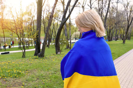 Young Ukrainian woman with the flag of Ukraine in the parkの写真素材
