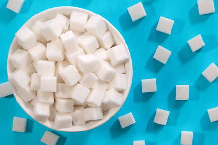White sugar cubes in a bowl on a blue background. Refined cane sugar.の写真素材