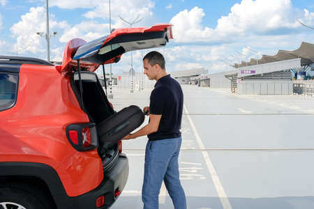 A man puts a suitcase in the trunk of a car. Business tripの写真素材