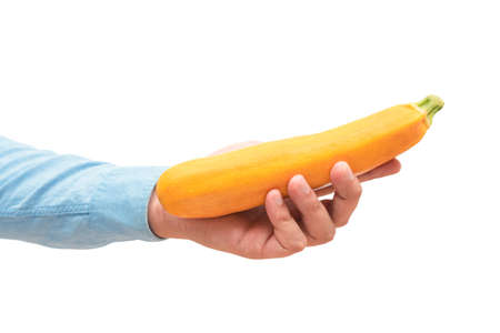 Male hand holding yellow zucchini isolated on white background. Organic productsの写真素材