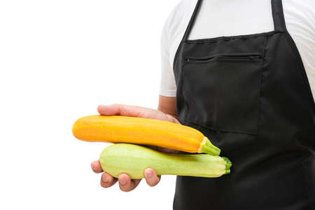 Zucchini vegetables in the hand of a man in an apron isolated on a white background. Cooking conceptの写真素材