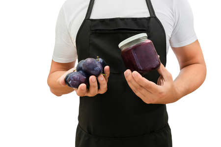 Fresh plums and a jar of jam in the hands of a cook isolated on a white background. The concept of...