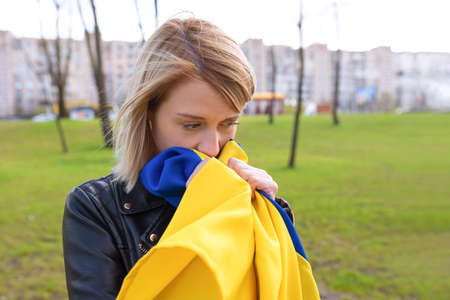 Outdoor portrait of a sad woman with Ukraine flag outdoors in the park. Free lifestyle conceptの写真素材