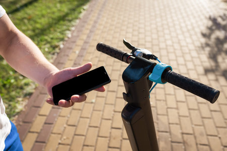 The hand of a person using a smartphone for an electric scooter on the street. Urban lifestyleの写真素材
