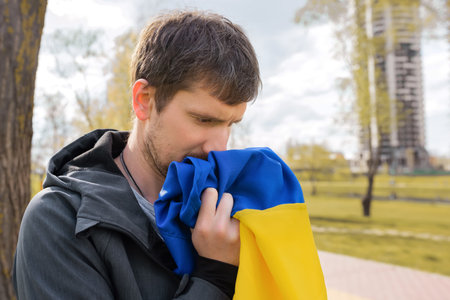 Outdoor portrait of a man holding the flag of Ukraine in the city street close-up.の写真素材